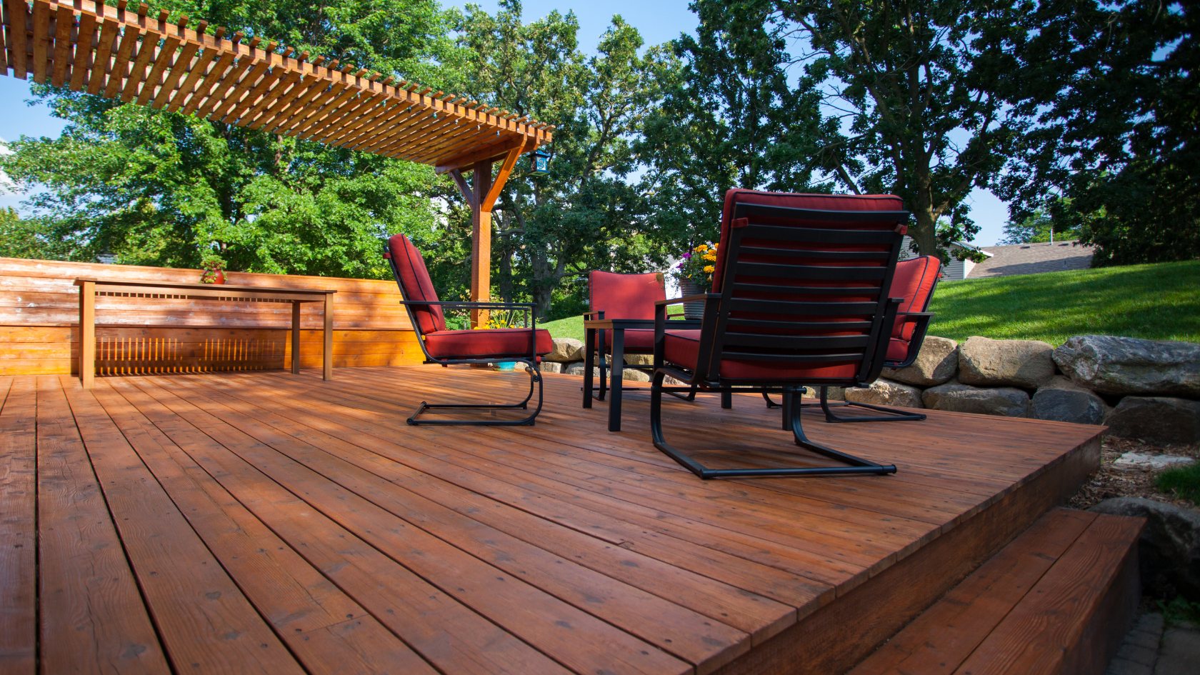 A wooden deck with chairs and a pergolated area